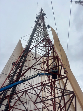 Upward perspective of 596ft self-supporting broadcast tower with containment tarps